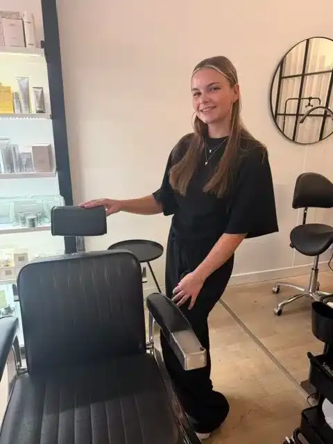 Fleur staat lachend bij de behandelstoel in de salon.